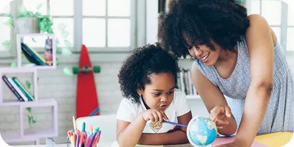 Teacher and young student looking at a globe. 