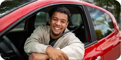 Young man in a red vehicle smiling